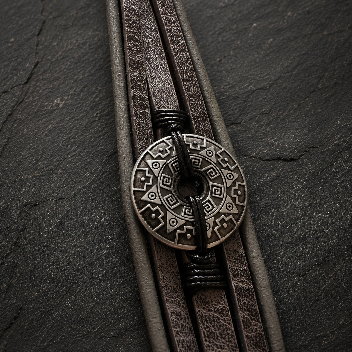 Close-up of grey multi-strand bracelet featuring a silver-tone patterned disc.