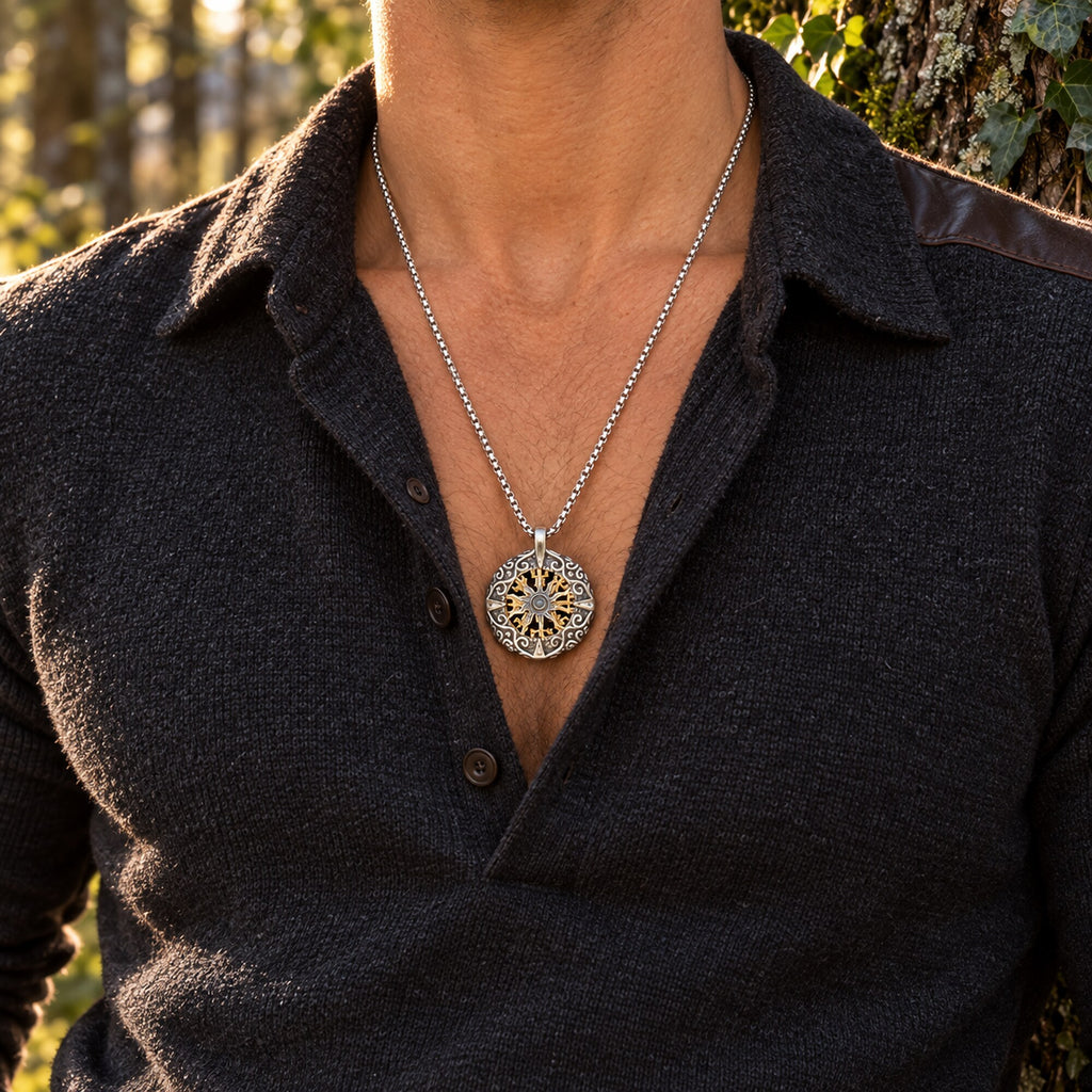 Close-up of Nordic compass pendant necklace with gold-tone radial symbol and silver-tone ornamental frame.