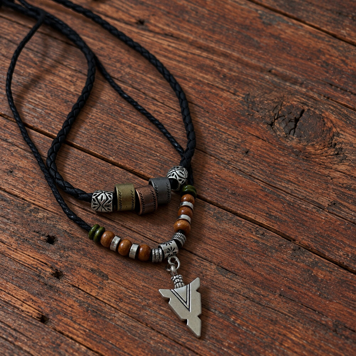 Close-up of black cord Norse Traveller Arrow Amulet necklace with decorative beads and silver-tone arrowhead pendant.