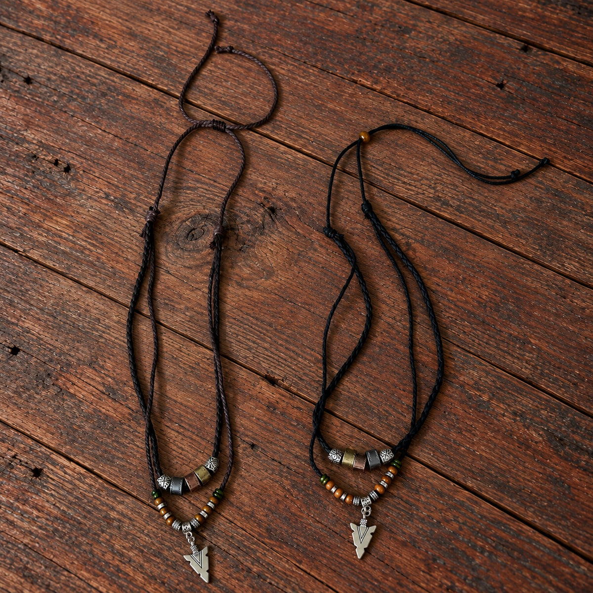 Brown and black Norse Traveller Arrow Amulet necklaces with layered cords, beads and silver-tone arrow pendants.
