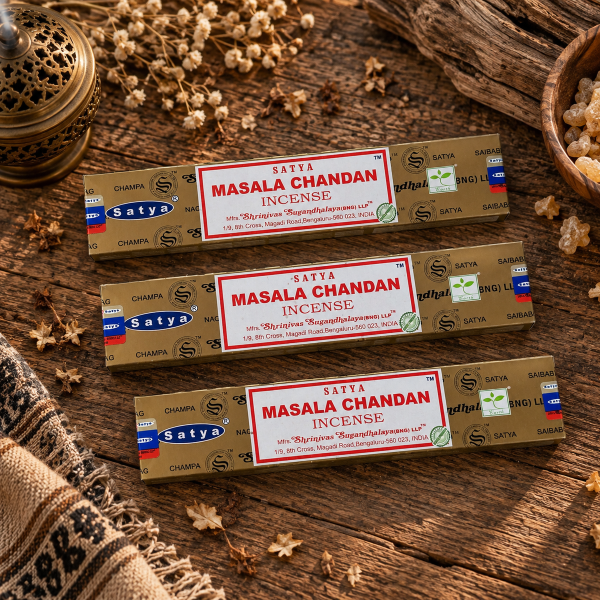 Satya Masala Chandan Incense Sticks 15g displayed on rustic wood with dried botanicals, resin and an incense burner.