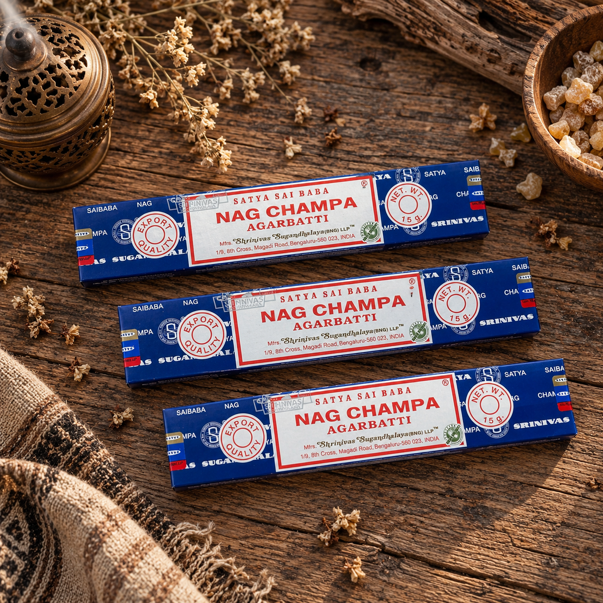 Satya Sai Baba Nag Champa Incense Sticks 15g displayed on rustic wood with dried botanicals and incense accessories.