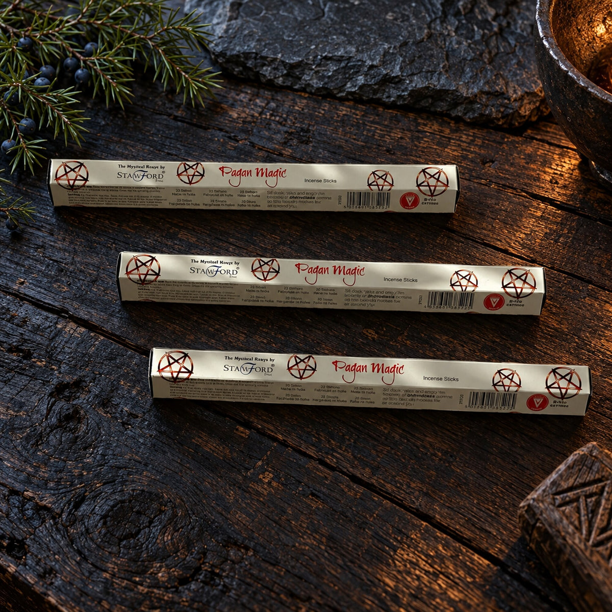Stamford Pagan Magic Aphrodesia incense stick packs displayed on a dark rustic wooden surface with juniper branches.