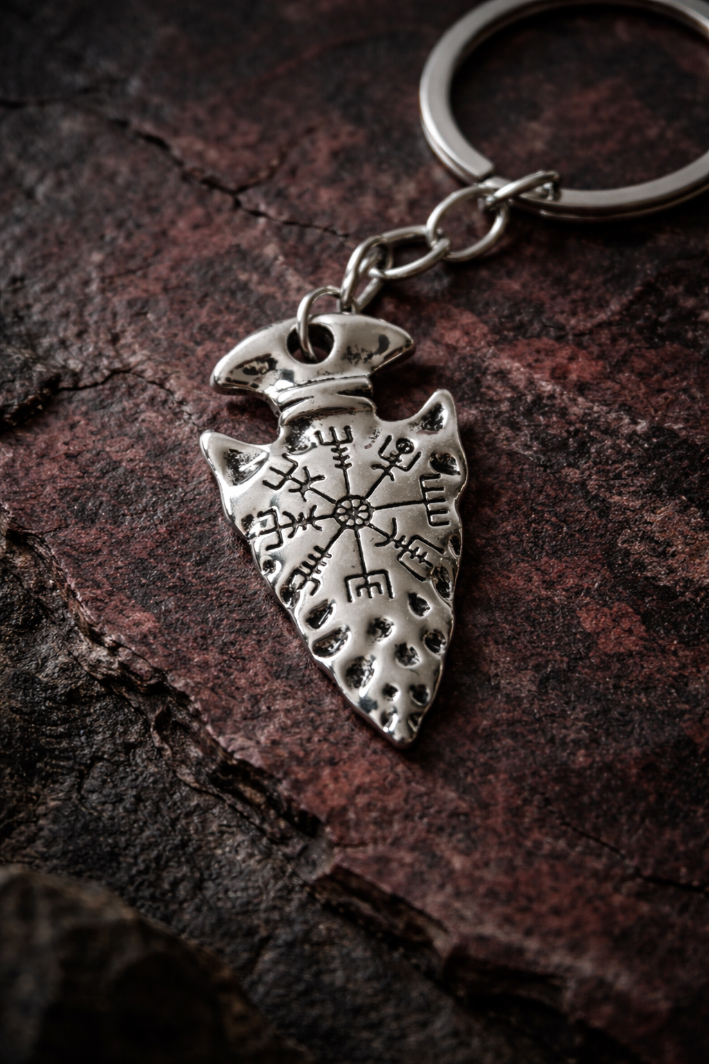 Close-up of a silver-tone arrowhead-shaped keychain charm engraved with a Vegvísir runic symbol