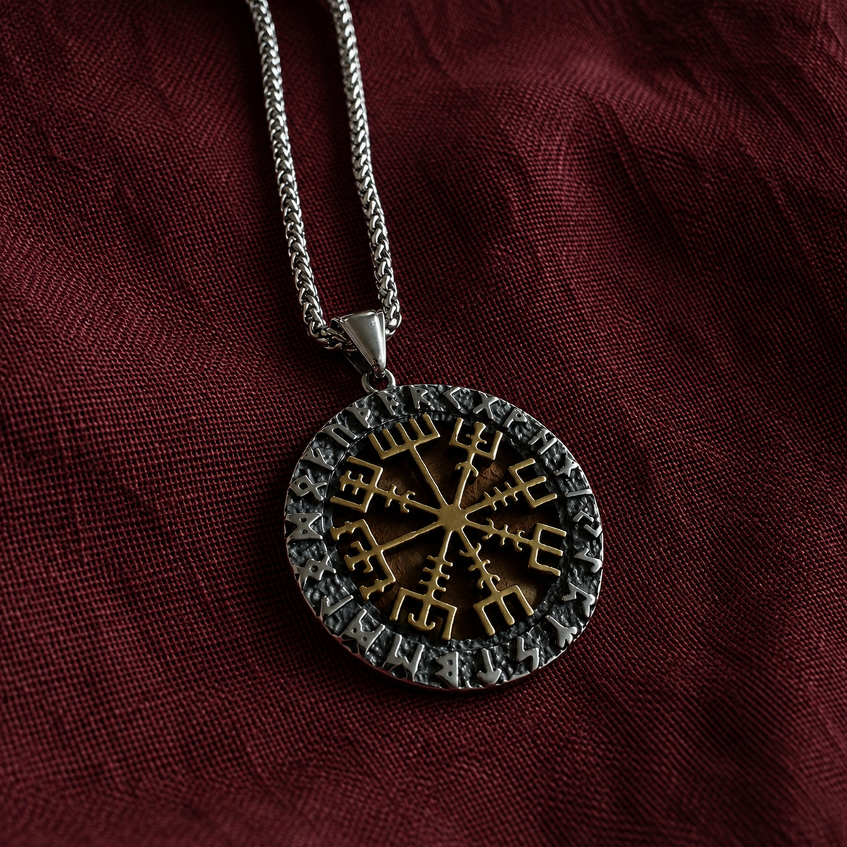Close-up of a round Vegvísir rune pendant with a gold-tone compass symbol and dark runic border on a silver-tone chain